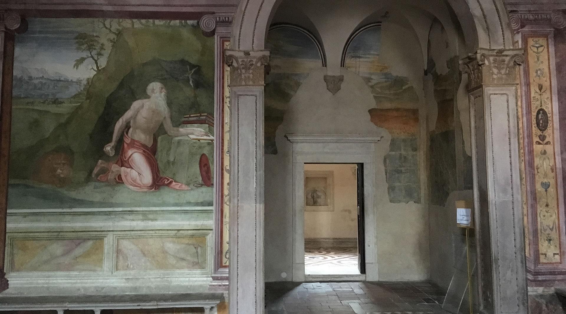 Renaissance fresco in Spoleto Cathedral depicting Saint Jerome in prayer, decorated columns, and an open doorway to another room.