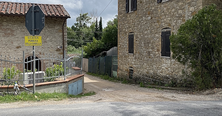 Gravel path between two stone buildings, with a sign reading 