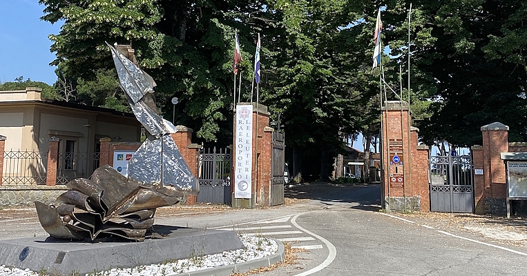 Eingang mit Backsteinpfeilern, Flaggen und einer modernen Metallskulptur am Eingang des Flughafens Eleuteri.