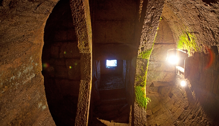 Vue en contre-plongée de l’entrée du puits, avec sa voûte à double treillis construite avec de grands blocs de travertin