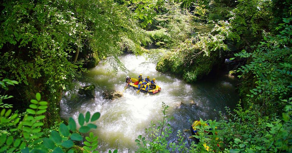 Bateau de rafting jaune au milieu d’une rivière à la végétation luxuriante