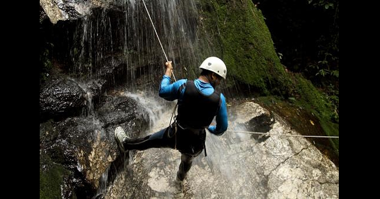 Person canyoning by abseiling inside a small canyon with safety equipment