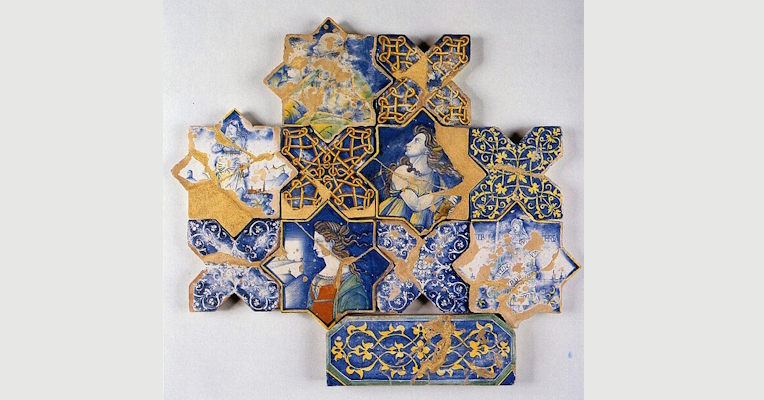 Floor of the Church of San Francesco in Deruta, on display at the Deruta Ceramics Museum. The composition features ceramic tiles in star-shaped and rectangular shapes. Some tiles depict human figures, including women with Renaissance features, while others show intricate geometric and floral motifs in blue, yellow and white.