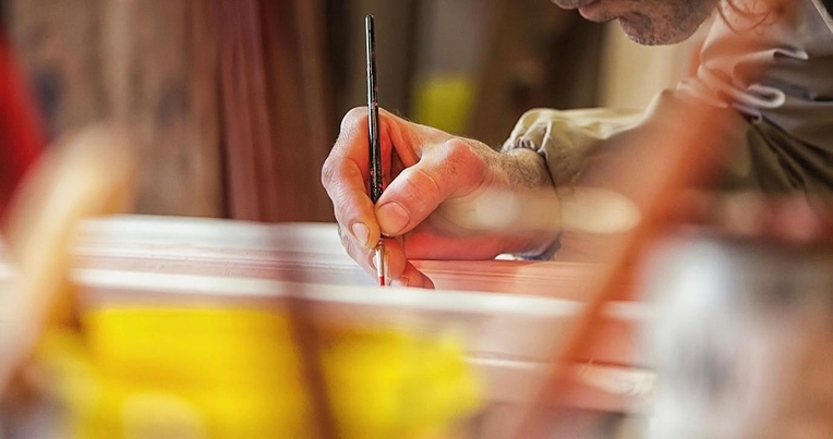 La main d'un artisan peignant une création en céramique.