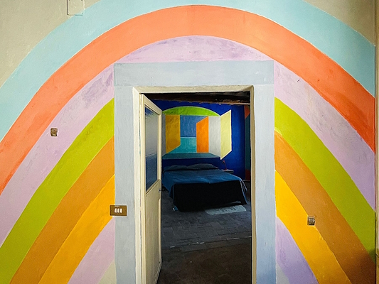 Entrance with painted rainbow arches leading to a room with vibrant geometric wall designs.