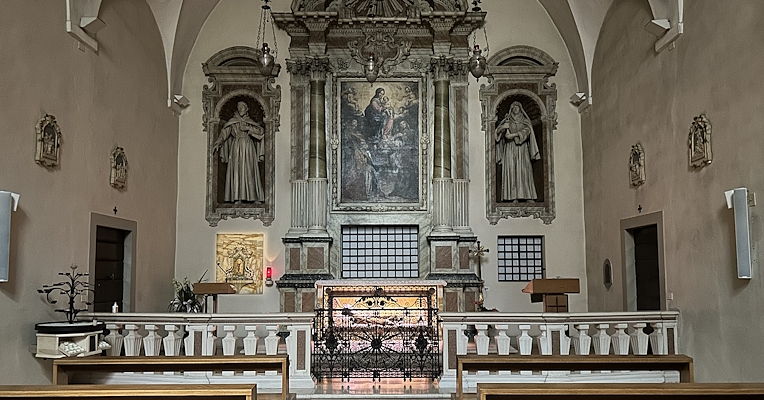 Innenkapelle mit Altar, Statuen an den Seiten und zentralem Gemälde, Blick von den Holzbänken, ruhige Atmosphäre und Gewölbebögen.