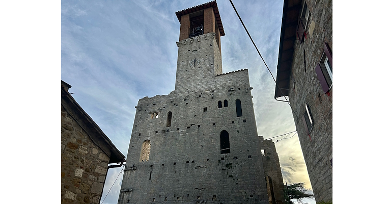 Facciata frontale del Castello di Agello, caratterizzata da antiche finestre e dominata da un maestoso campanile che svetta sull'edificio