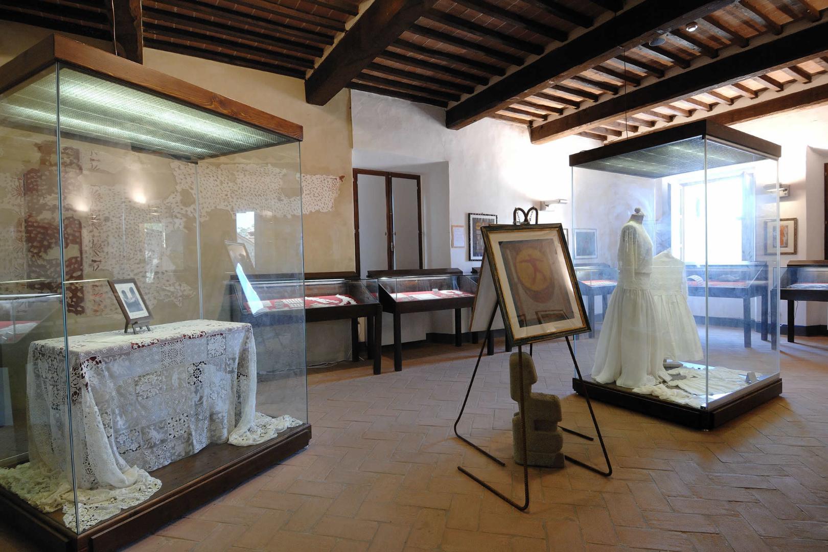 Vue large d'une salle du Musée de la Dentelle, où sont exposées diverses œuvres textiles, y compris des dentelles et broderies raffinées.